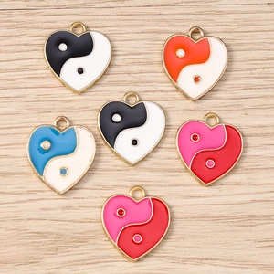 Close-up of heart-shaped Yin Yang enamel charms with golden borders for DIY jewelry