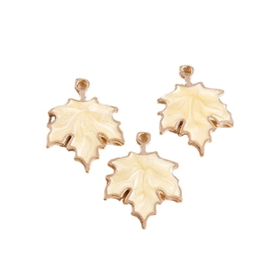 Three cream-colored maple leaf enamel pendants with golden alloy edges on white background