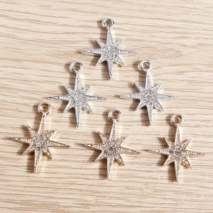 Sparkling gold and silver star pendants with artificial diamonds on light wood background