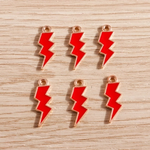 Detail of six red lightning bolt charms with gold plating on a wooden surface