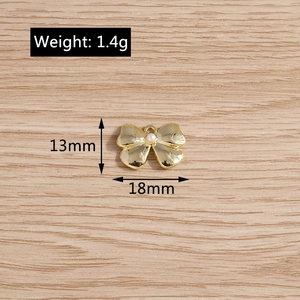 Detail of bow-shaped pendant with faux pearl and gold plating for DIY jewelry