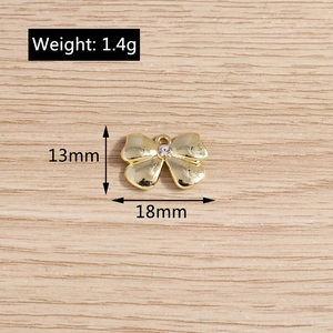 Macro view of gold bow pendant with crystal showing 13mm height and 18mm width dimensions