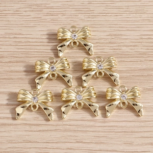 Vue détaillée des pendentifs nœuds dorés avec strass et anneaux doubles pour bijoux artisanaux