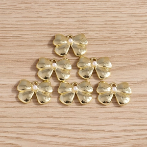 Detailed view of golden bow pendants with pearl centers for DIY jewelry making