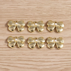 Detail of golden bow charms with white pearls for DIY jewelry making and accessories