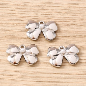 Detail of silver bow pendants with faux pearl inlay for DIY jewelry making and crafts