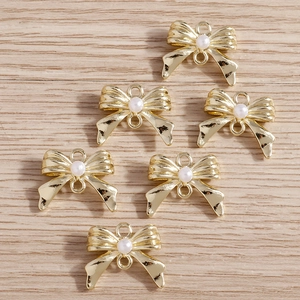 Détail de six pendentifs nœuds dorés avec perles pour la fabrication de bijoux DIY
