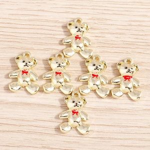 Detailed close-up of golden alloy bear charms with red bow ties on a wooden surface