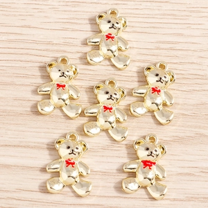 Detailed view of six golden alloy bear pendants with red bows on a wooden background
