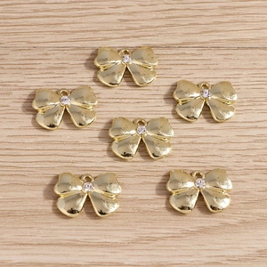 Golden bow jewelry pendants set with central rhinestones and top hanging loops