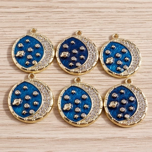 Celestial planet moon charms with blue enamel and white rhinestones on light wood background