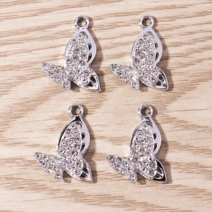 Macro detail of four silver butterfly pendants with white rhinestones and hollow wings