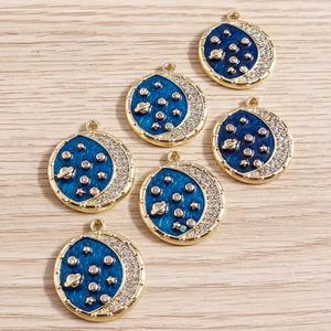 Detail of star and moon planet pendants with blue enamel and gold alloy plating