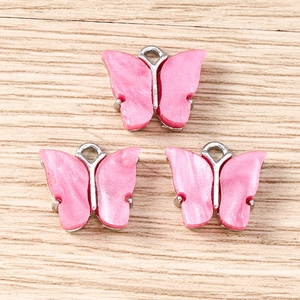 Detailed view of pink pearl texture acrylic butterfly charms with silver metal frames