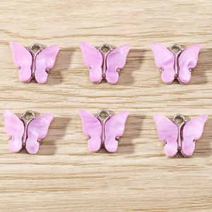 Macro detail of six pink resin butterfly pendants with silver metal frames for DIY jewelry
