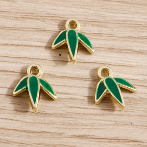 Detailed macro view of three golden bamboo leaf pendants with vibrant green enamel finish