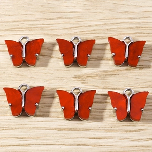 Set of six vibrant red butterfly pendants with silver metal edges on wooden surface