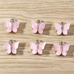 Detailed view of six pink butterfly charms with silver metal rings on a wooden surface