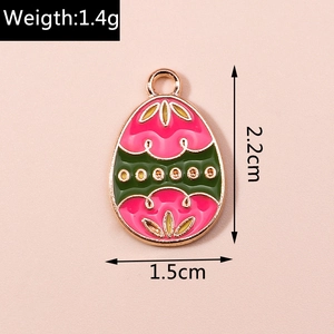 Macro view of rose pink and dark green enamel Easter egg charm with gold wave patterns