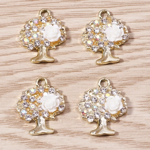Dettaglio dei pendenti a forma di albero dorati con strass e rose in resina bianca