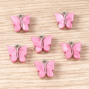 Detailed macro view of pink pearlescent acrylic butterfly charms with silver metal centers