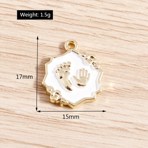 Detail of octagonal gold metal pendant with white enamel hand and footprints, 17x15mm size
