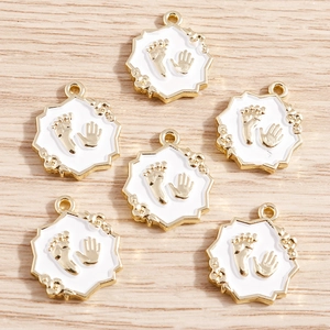 Detail of alloy handprint and footprint pendants with gold plating and white enamel