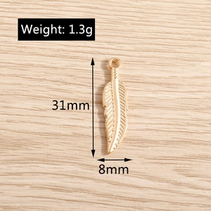 Detail view of gold alloy feather pendant with 31mm length and 1.3g weight dimensions
