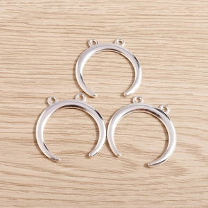 Macro view of three silver crescent moon pendants with double loops on wood surface