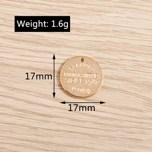 Macro detail of a 17mm round gold metal letter pendant with textured vintage engraving
