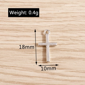 Detail view of small silver cross pendant with dimensions 18mm x 10mm and 0.4g weight