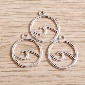 Minimalist silver circular wave pendants for DIY jewelry making displayed on a wooden surface