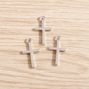 Detailed view of silver alloy cross pendants for DIY jewelry making on wooden background