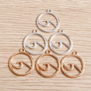 Detail of silver and rose gold wave pendants on wooden surface for jewelry making