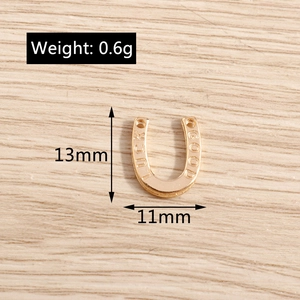 Detail van een 13mm gouden hoefijzer gelukshanger met gegraveerde tekst voor DIY