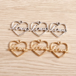 Golden and silver heart-shaped Love pendants for DIY jewelry making on wood background