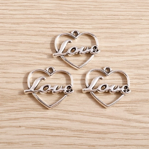 Set of three silver-plated heart pendants with Love cutout on light wood background