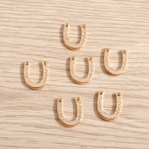 Macrodetail van gouden hoefijzerbedeltjes met GOOD LUCK-gravure voor DIY-sieraden