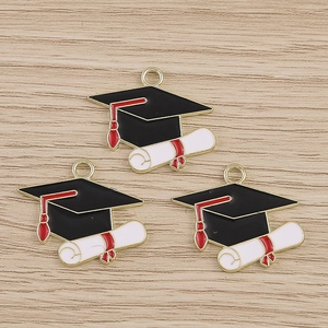 Close-up of alloy graduation cap charms with red tassels on wooden background