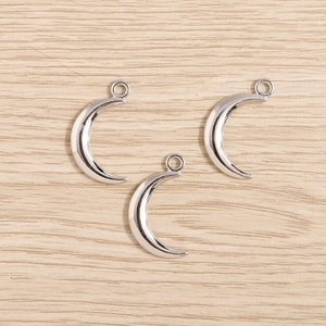 Three silver crescent moon charms in plated alloy for DIY jewelry making on wood background
