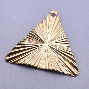 Macro detail of a 18k gold-plated 304 stainless steel triangle charm with sunburst texture