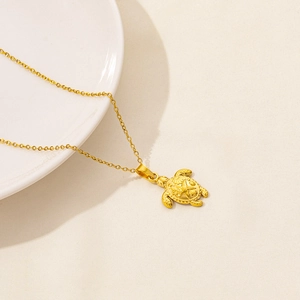 Detailaufnahme eines goldenen Meeresschildkröten-Anhängers mit feinen Sternschnitzereien