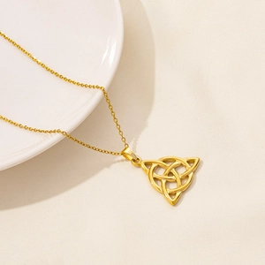 Dettaglio del pendente dorato a nodo celtico su una catena sottile per collana elegante