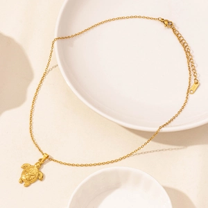 Detail einer goldenen Schildkröte mit Sternenmustern an einer Edelstahlkette