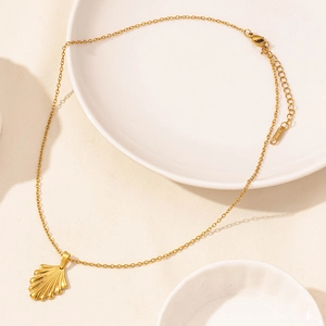 Dettaglio della collana dorata in acciaio inossidabile con pendente a conchiglia e tag