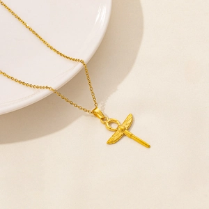 Collana con croce Ankh dorata e design ad ali su sfondo testurizzato minimal