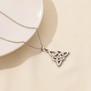 Macro di un ciondolo triquetra d'argento su una catena sottile con sfondo materico