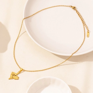 Dettaglio della collana dorata con ciondolo a cuore e freccia e ali d'angelo su ceramica