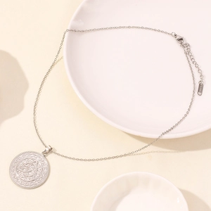 Dettaglio della collana in acciaio inossidabile con pendente nodo triquetra su vassoi bianchi