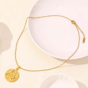 Dettaglio macro di una collana dorata con pendente a nodo celtico su piatto di ceramica